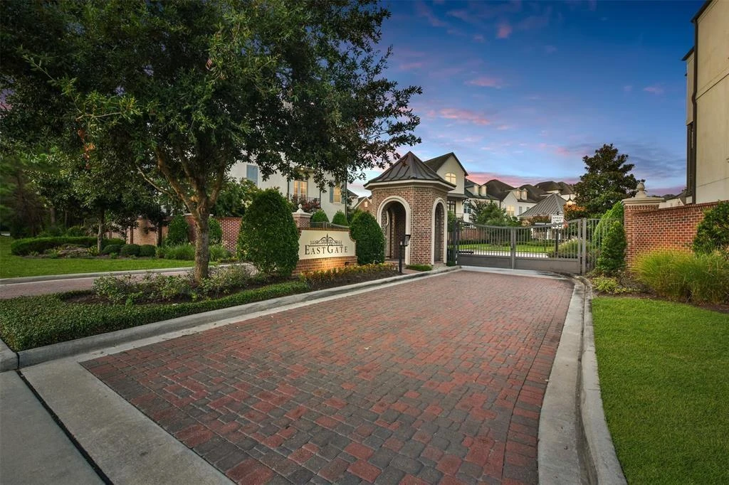 Brick-paved entrance with a gate, entry structure, landscaping, and an Eastgate sign.